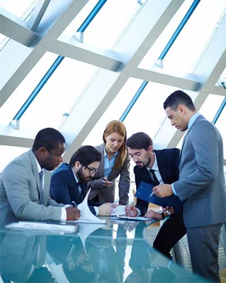 People working on a glass table represents our talents