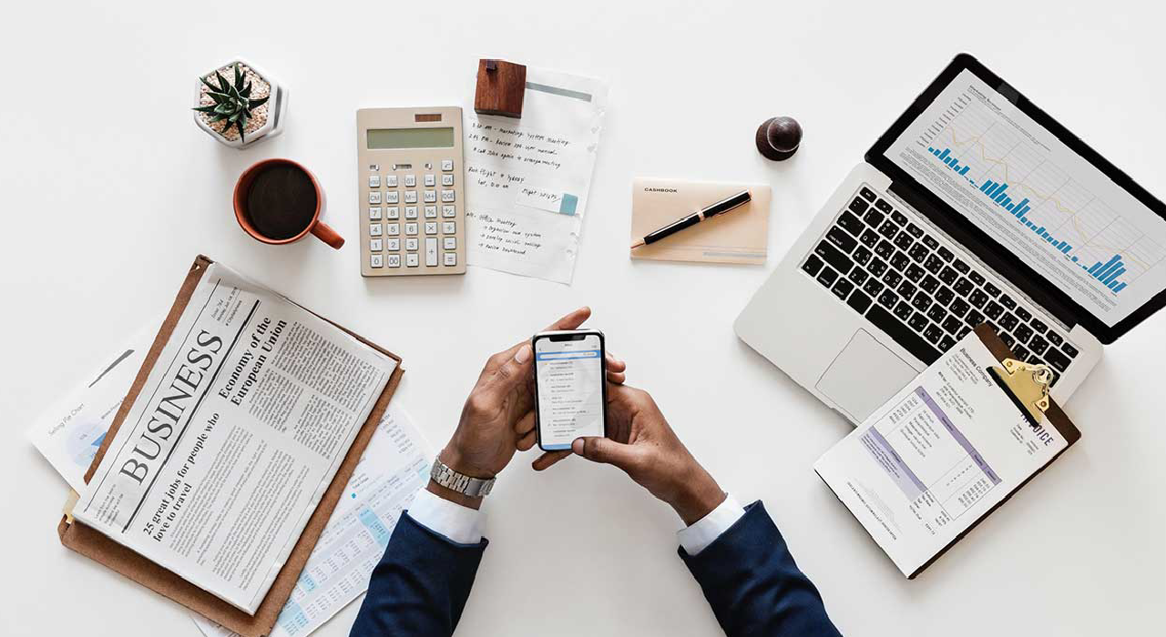 header, white desk with laptop a person using mobile phone represents our solution InsightsPMV for Primavera