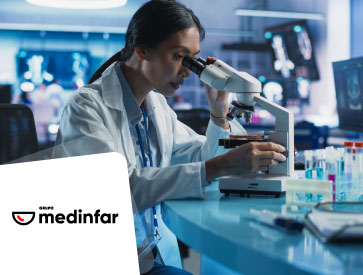 Woman in a laboratory looking at a sample through a microscope.